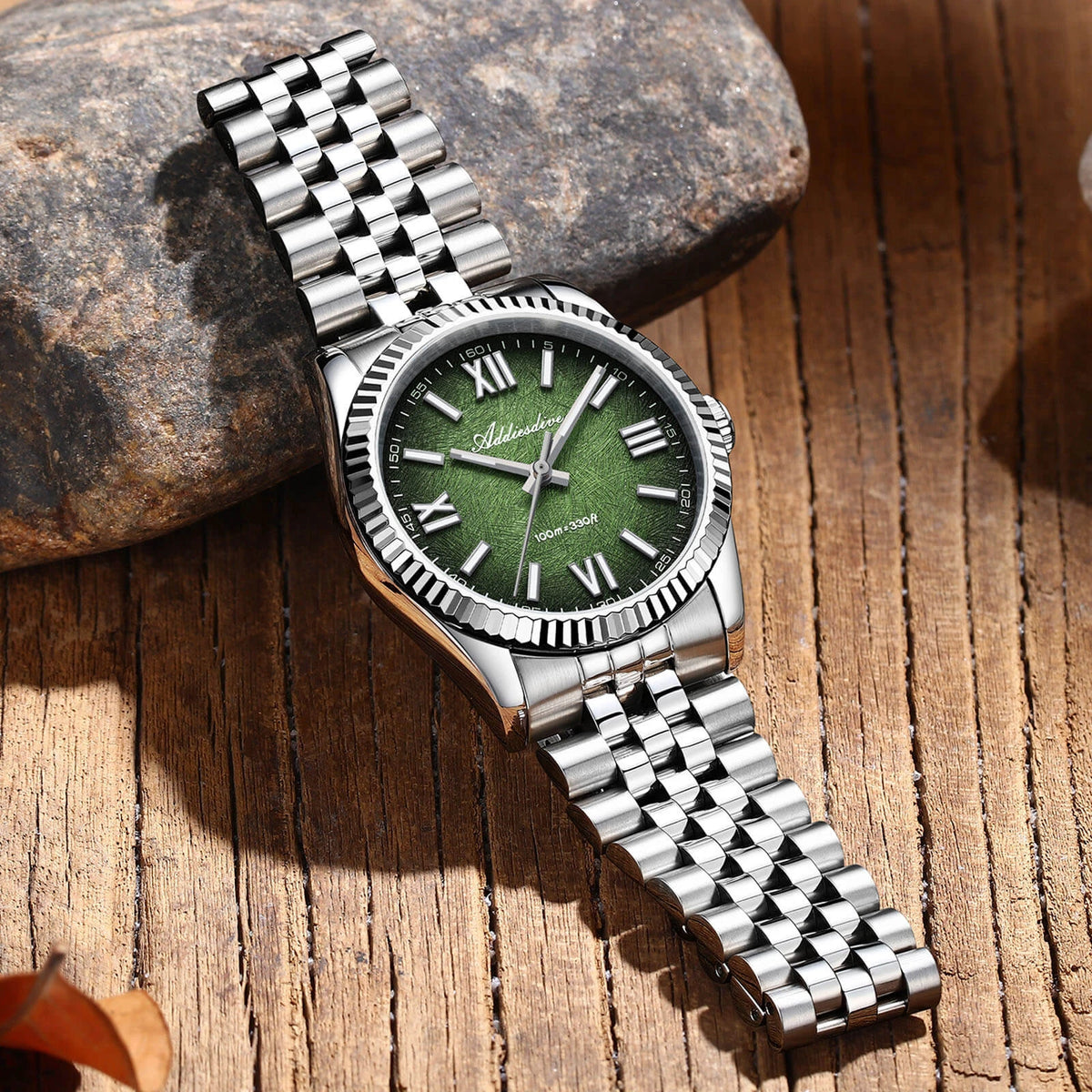 Calma watch with green dial and steel bracelet on stone and wood